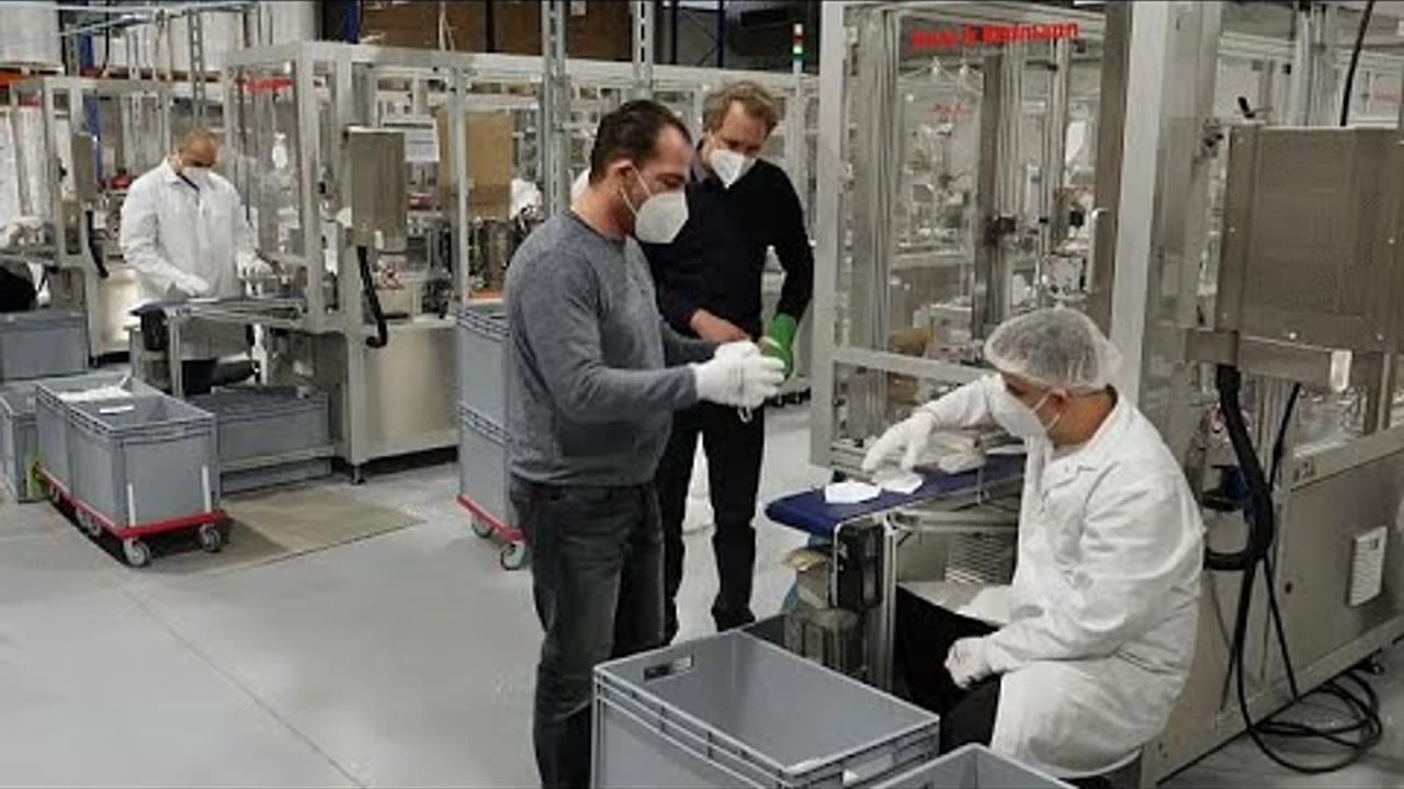 Vorschaubild: Gründer und Mitarbeitende in der Fertigung prüfen FFP2-Masken an der Produktionslinie